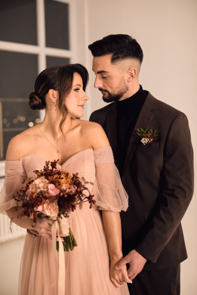 Paar in eleganter Kleidung, umgeben von romantischer Atmosphäre, mit einem Blumenstrauß.