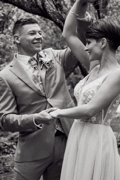 Ein Brautpaar tanzt glücklich unter einem Baum in einer romantischen Umgebung.