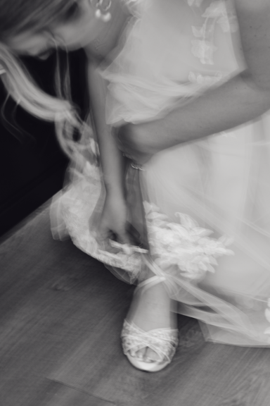 Ein Mädchen zieht einen Schuh an, während es in einem feinen Kleid sitzt.