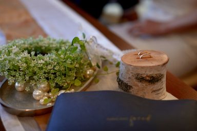 Blumenkranz, Silbertablett, Holzscheibe mit Ring, eleganter Hochzeitsstil.