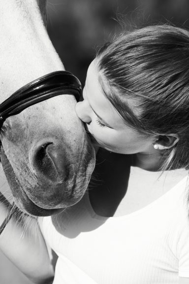 Eine Person küsst liebevoll das Maul eines Pferdes.