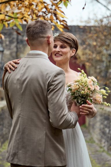 Braut und Bräutigam in eleganter Hochzeitskleidung umarmen sich im Freien.
