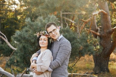 Junges Paar umarmt sich liebevoll vor einer idyllischen, natürlichen Kulisse.