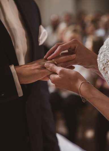 Hochzeit: Eine Person zieht einem anderen einen Ring an.